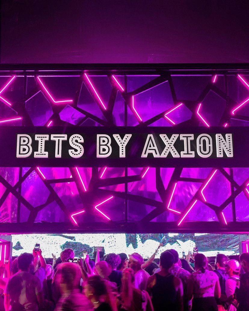 Cartel Bits by Axion sobre la estructura de neón rosa