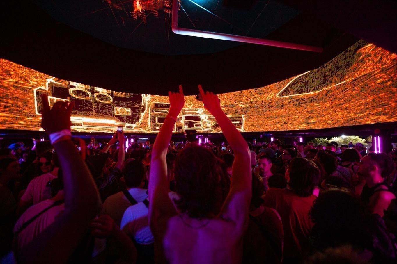 Público bailando bajo la pantalla curva del stand de Axion