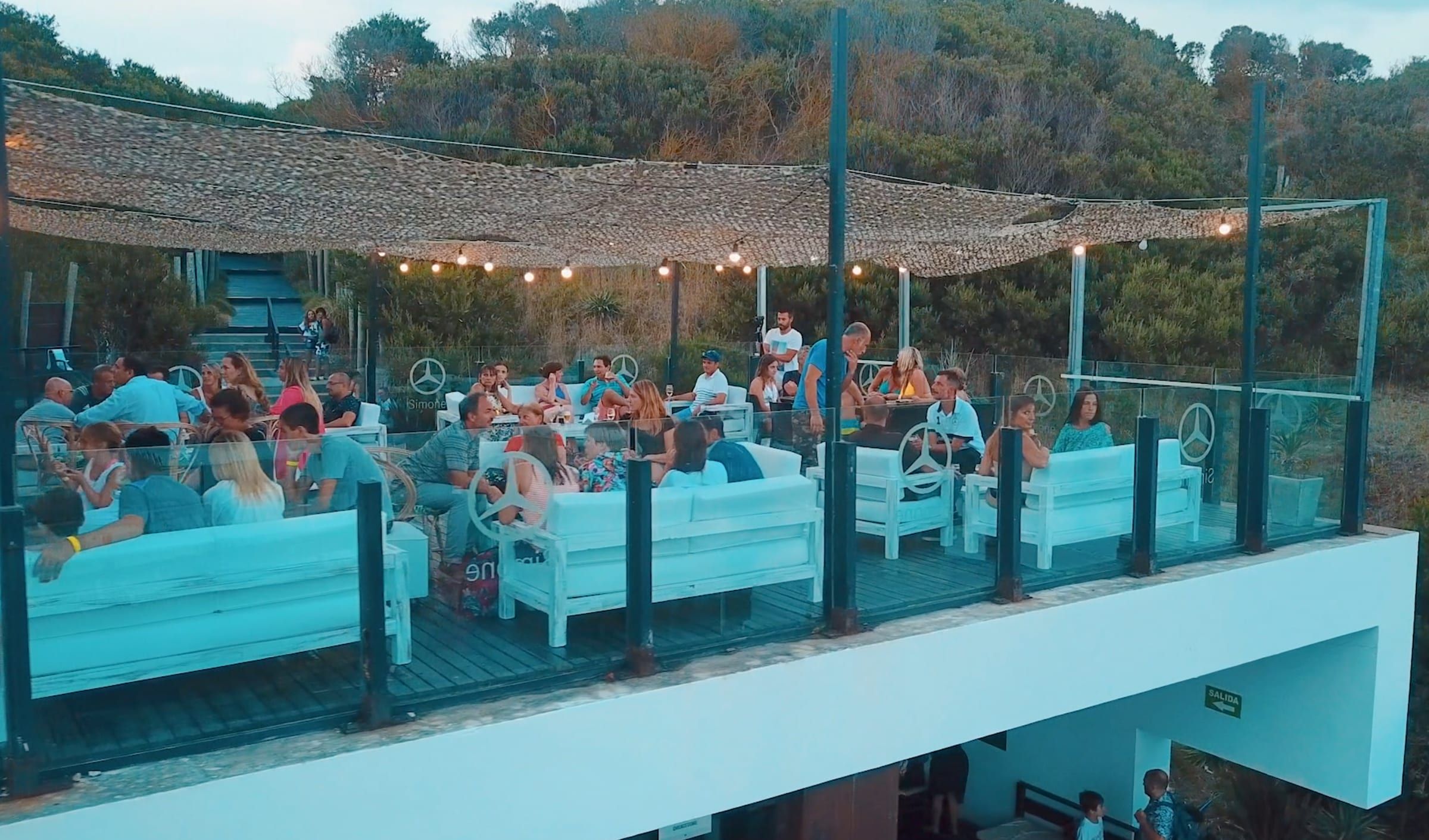 Deck del Balneario Cabolargo frente al mar, con público en un evento de verano