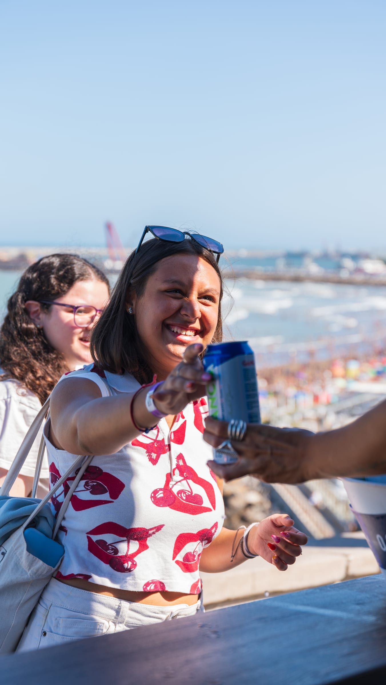 Promotora con lata de Gancia sin alcohol frente al mar en Mar del Plata