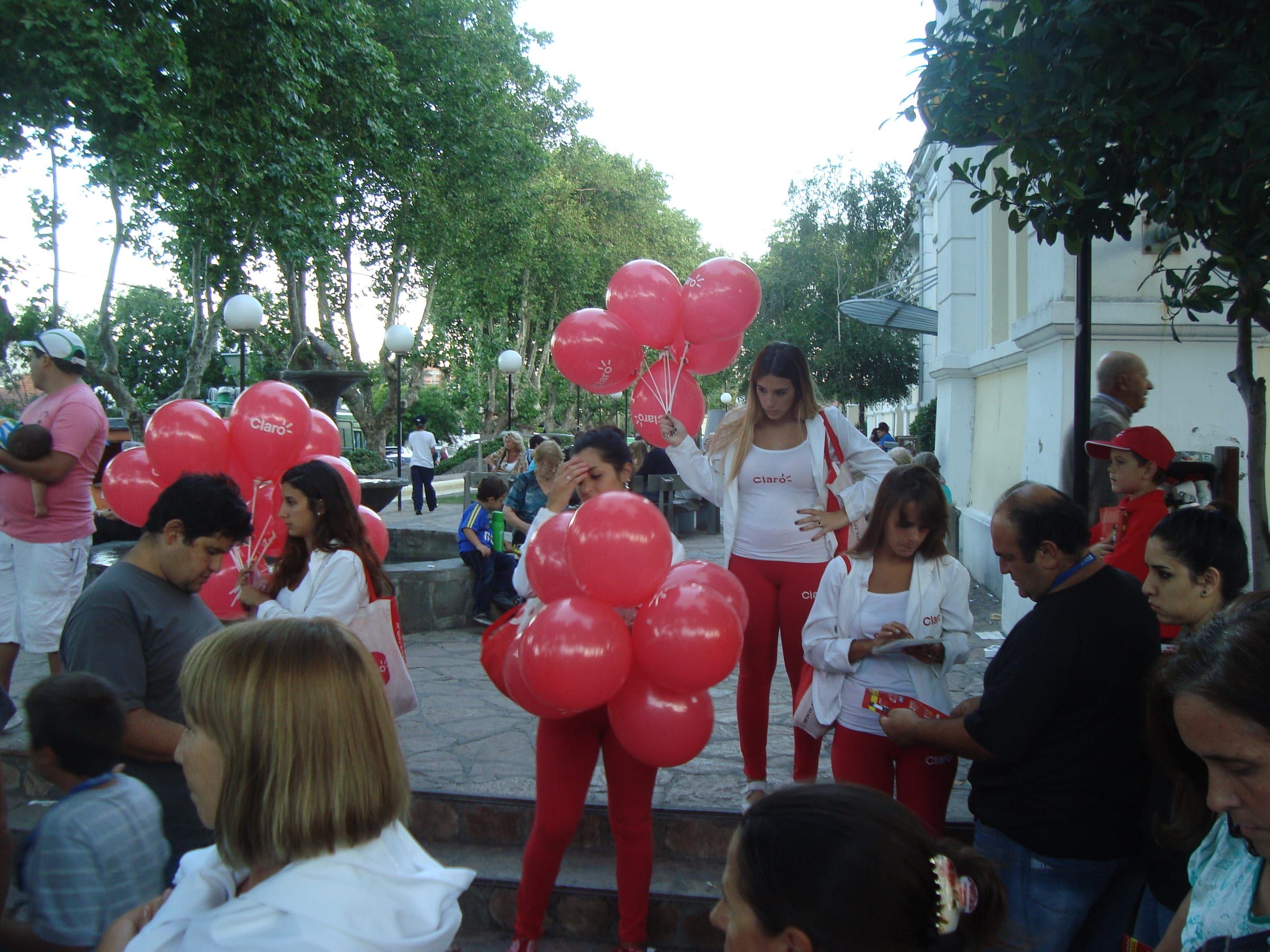 Brigada de Claro con globos rojos recorriendo una plaza