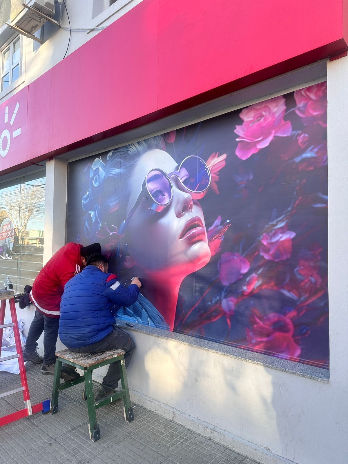 Dos instaladores colocando el vinilo de una vidriera de Claro