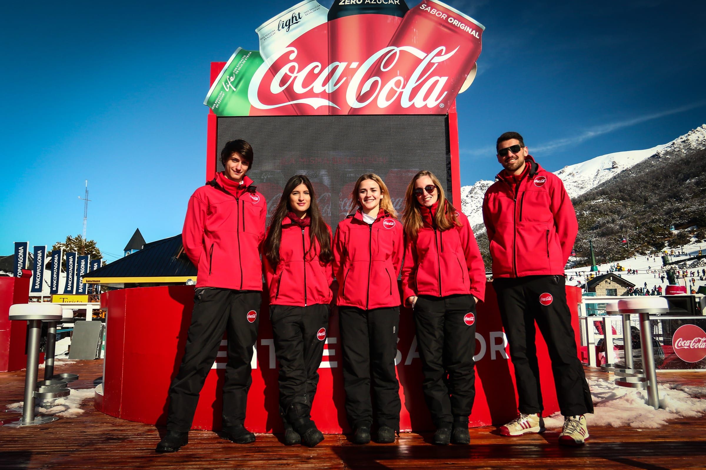 Equipo de promotores de rojo frente al parador de Coca-Cola en la nieve