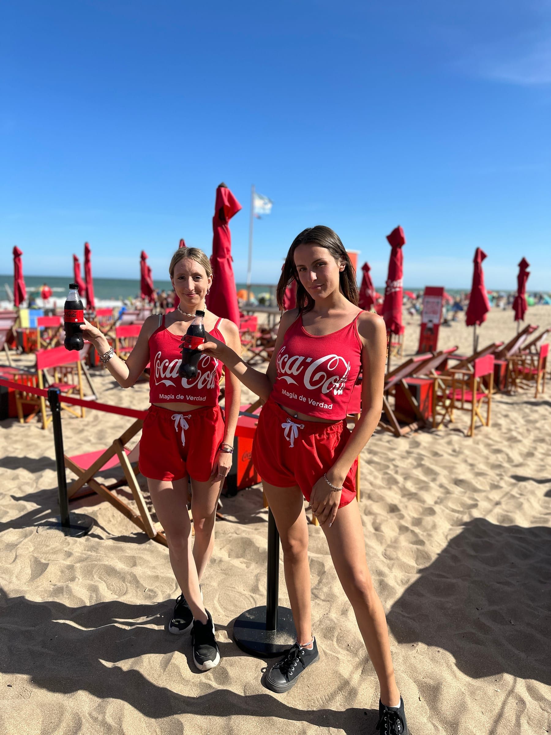 Brigada de promotoras y promotores de Coca-Cola con uniforme rojo