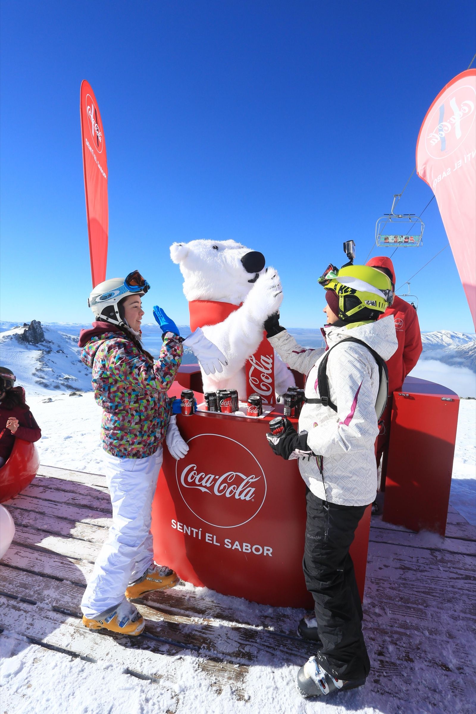Dos esquiadoras chocando los cinco con el oso polar de Coca-Cola