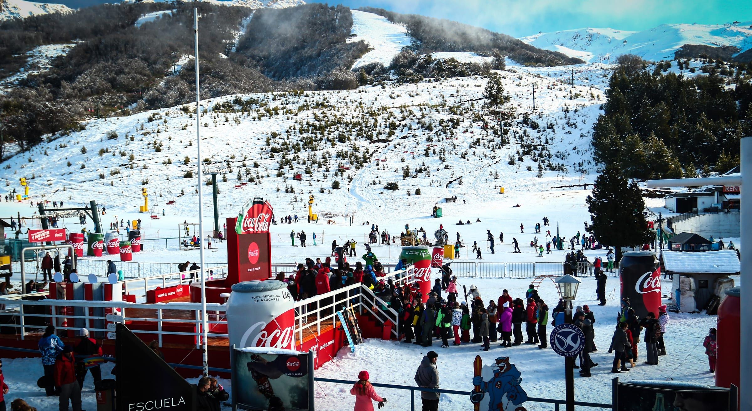 Parador de Coca-Cola al pie de las pistas del Cerro Catedral, con esquiadores alrededor