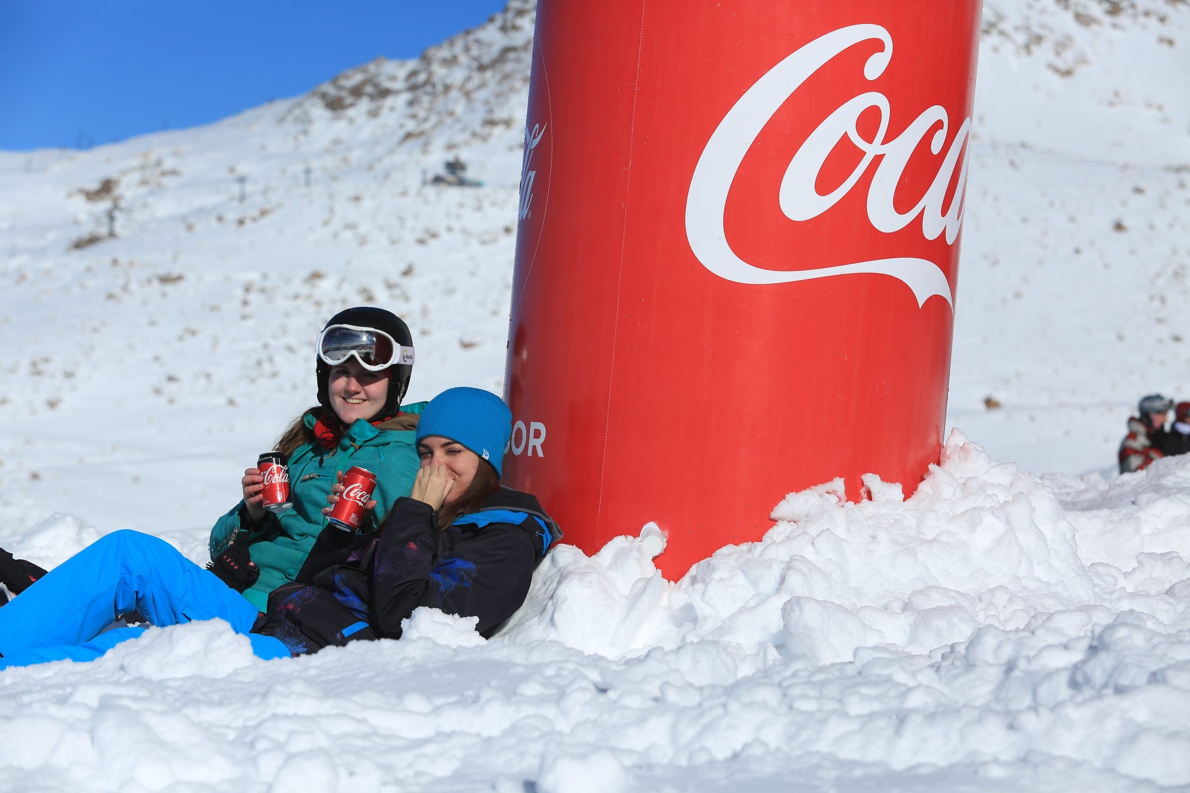 Esquiadores sentados junto a una lata gigante de Coca-Cola