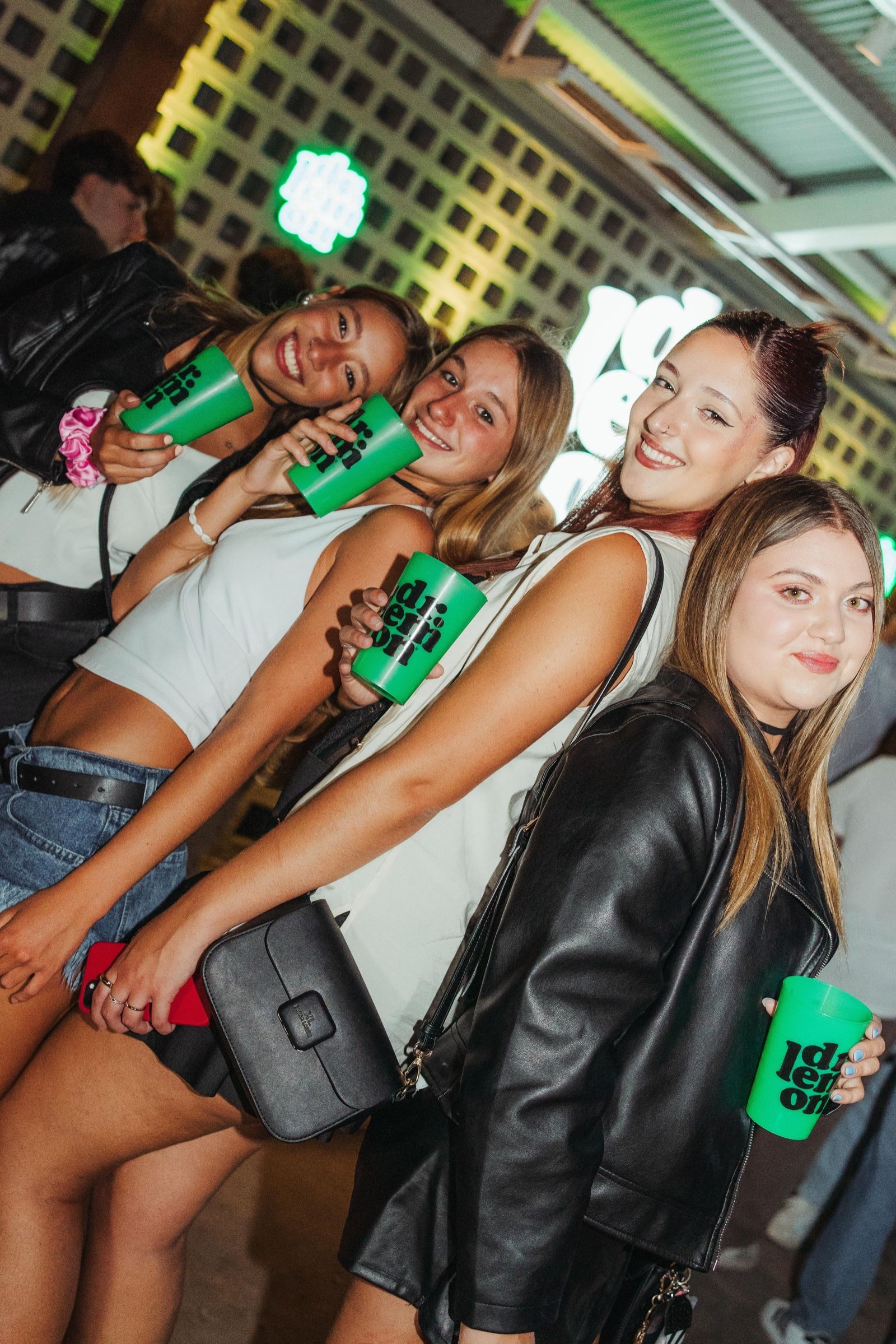 Cuatro amigas con vasos verdes de Dr. Lemon frente a la barra