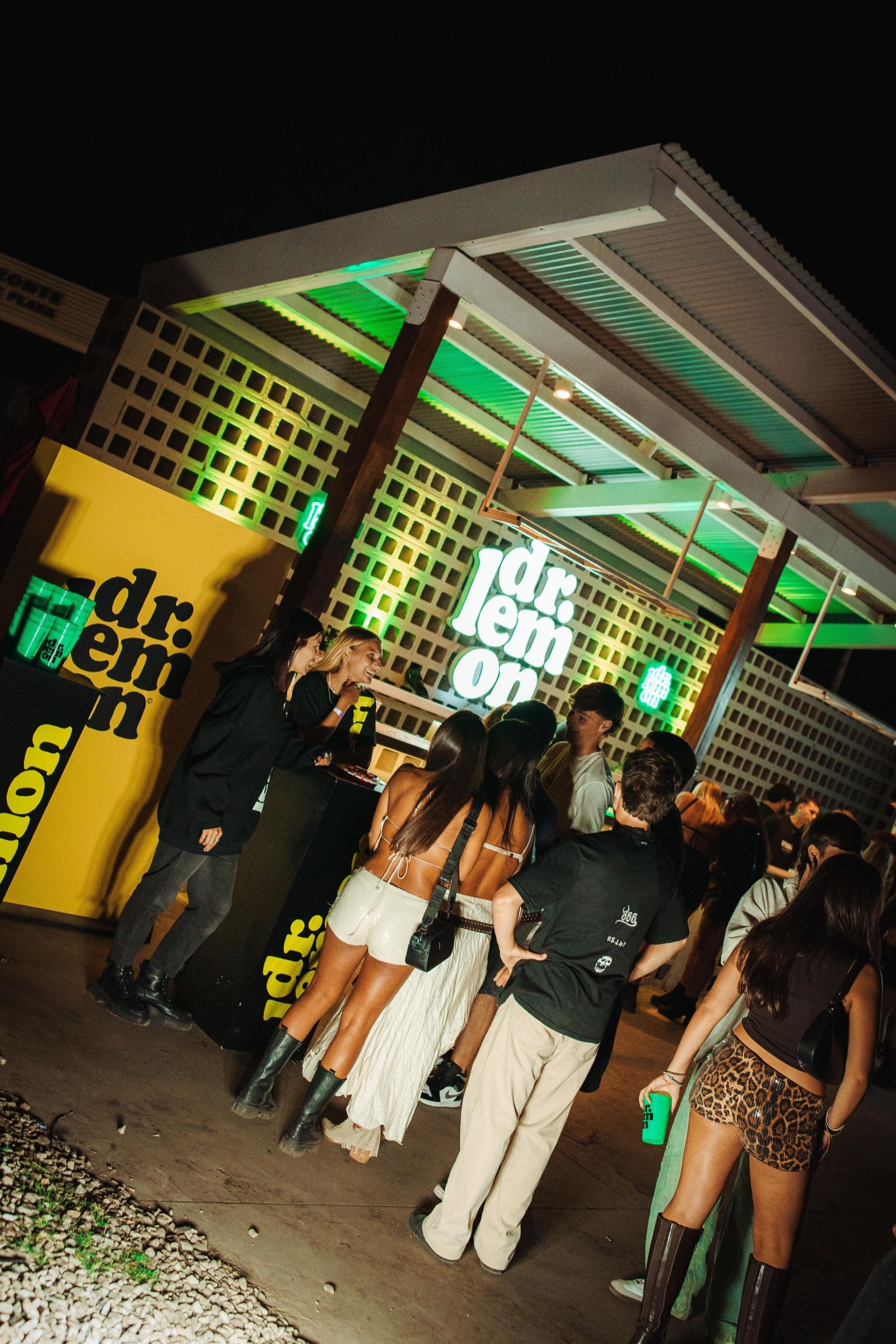 Barra de Dr. Lemon de noche, con el logo iluminado y público alrededor