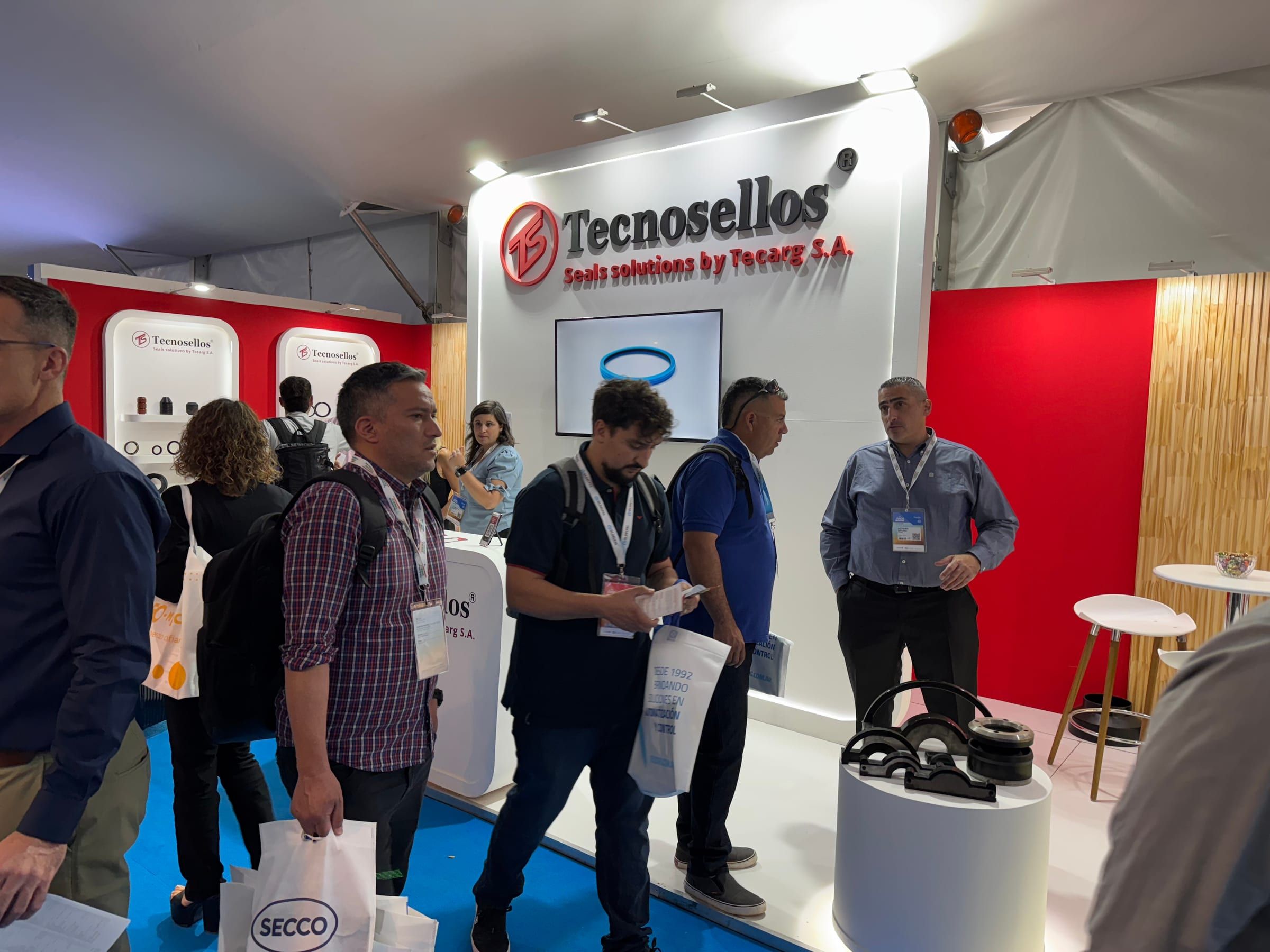 Visitantes conversando en el stand de Tecnosellos durante la feria