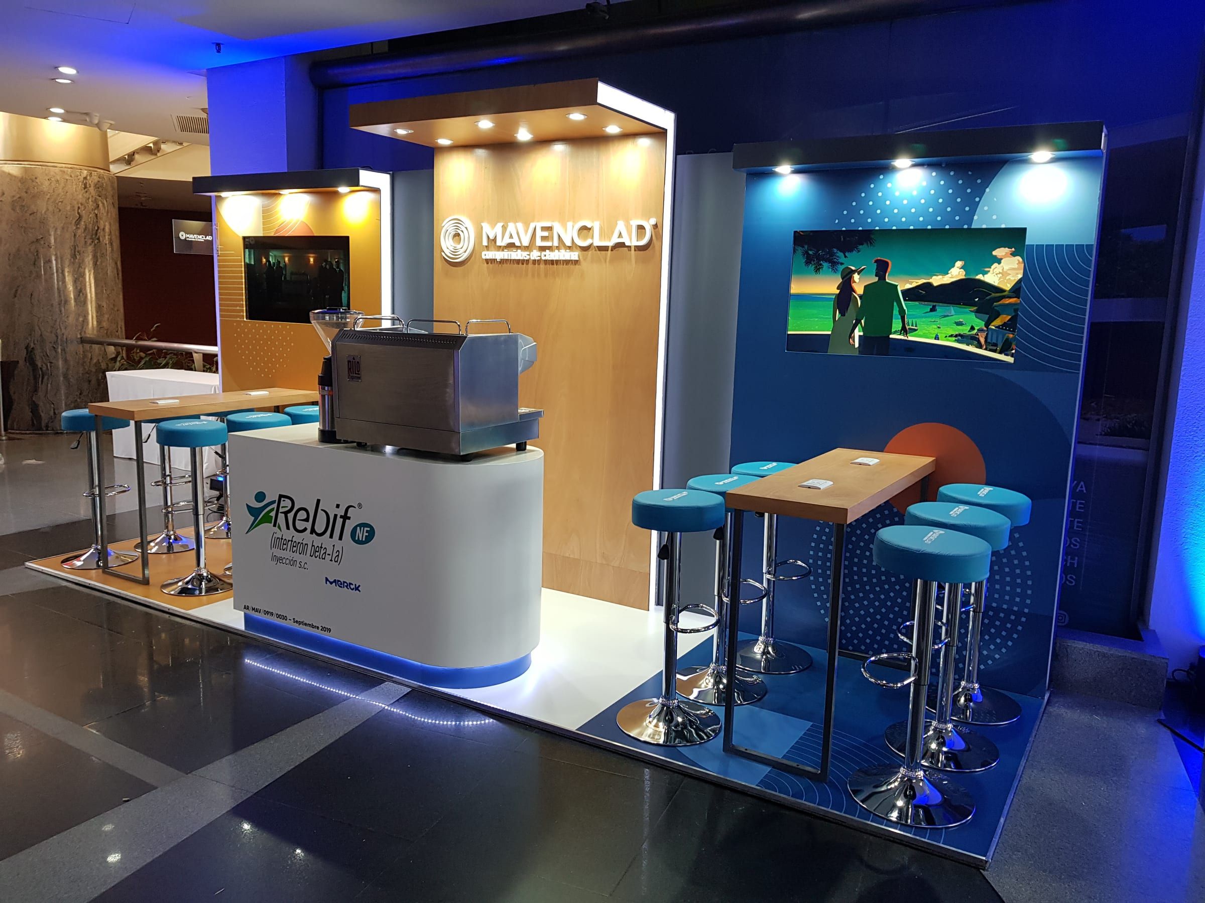 Stand de Mavenclad de Merck con barra de café y banquetas celestes