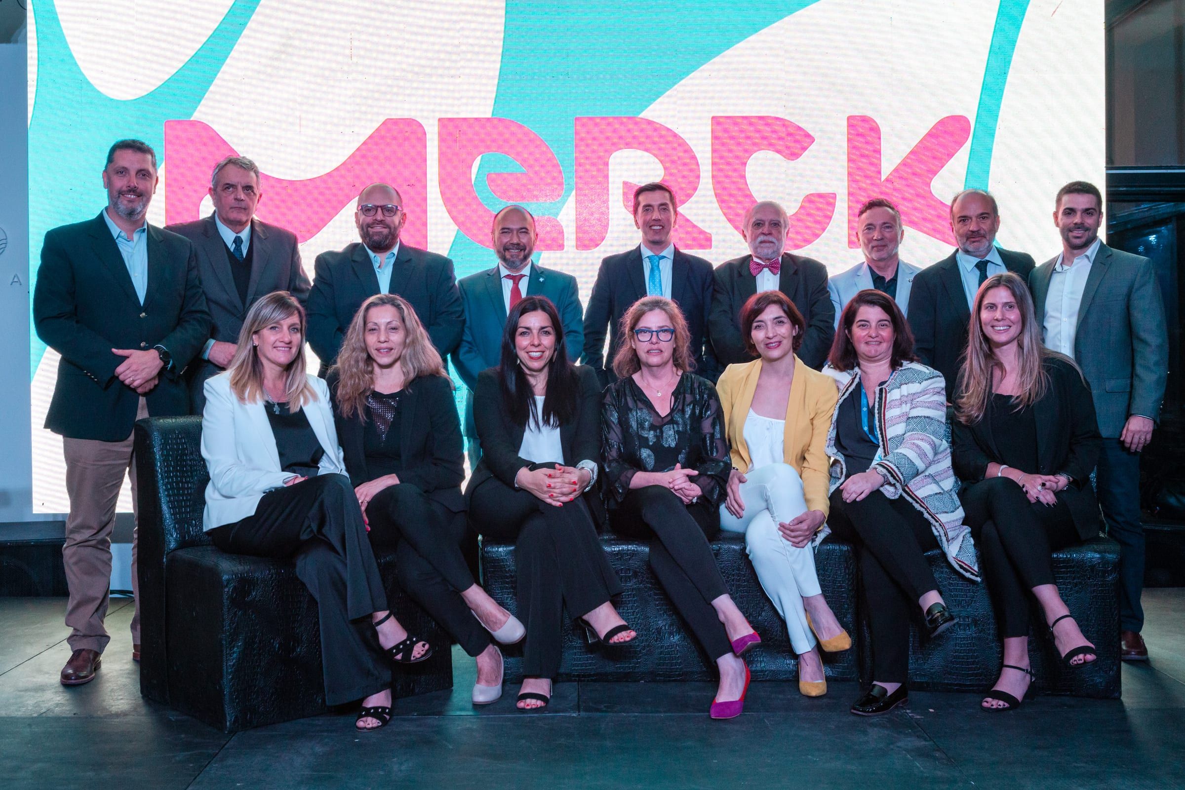 Equipo de Merck en el escenario frente al logo de la marca