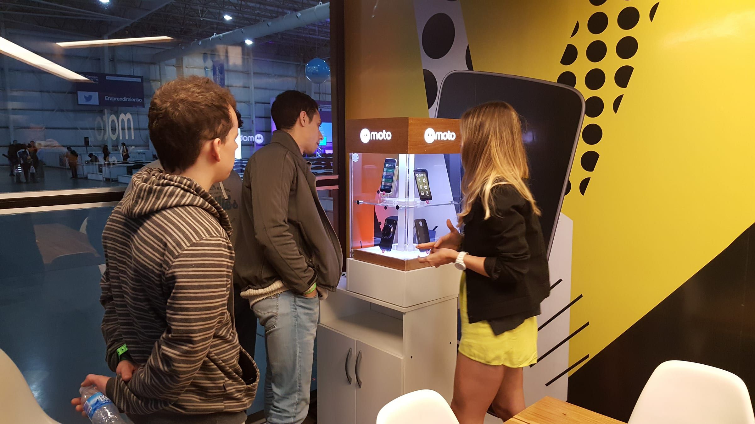 Visitantes probando los Moto Mods en el exhibidor del container