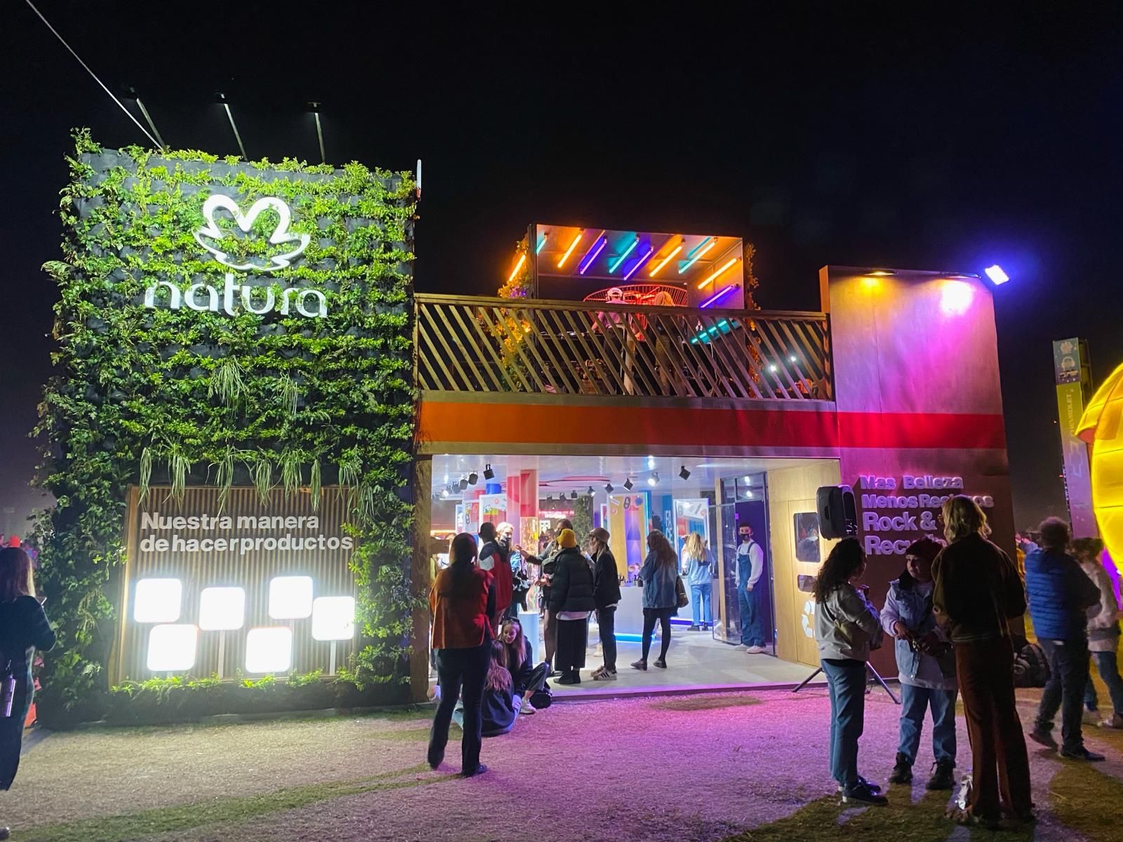 Frente del stand de Natura de noche, con el jardín vertical iluminado y la terraza arriba