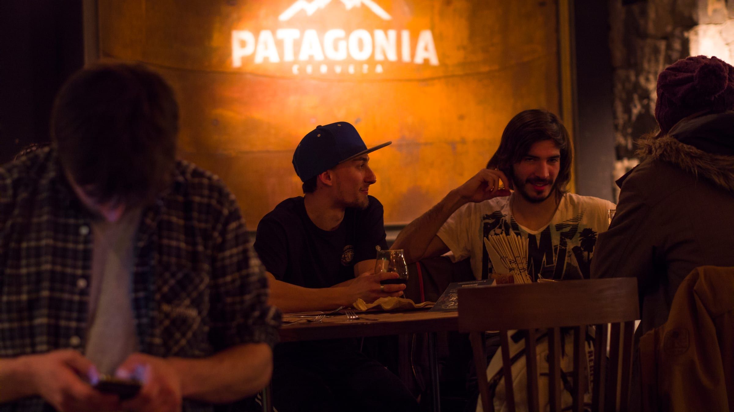 Amigos tomando cerveza bajo el cartel de Patagonia