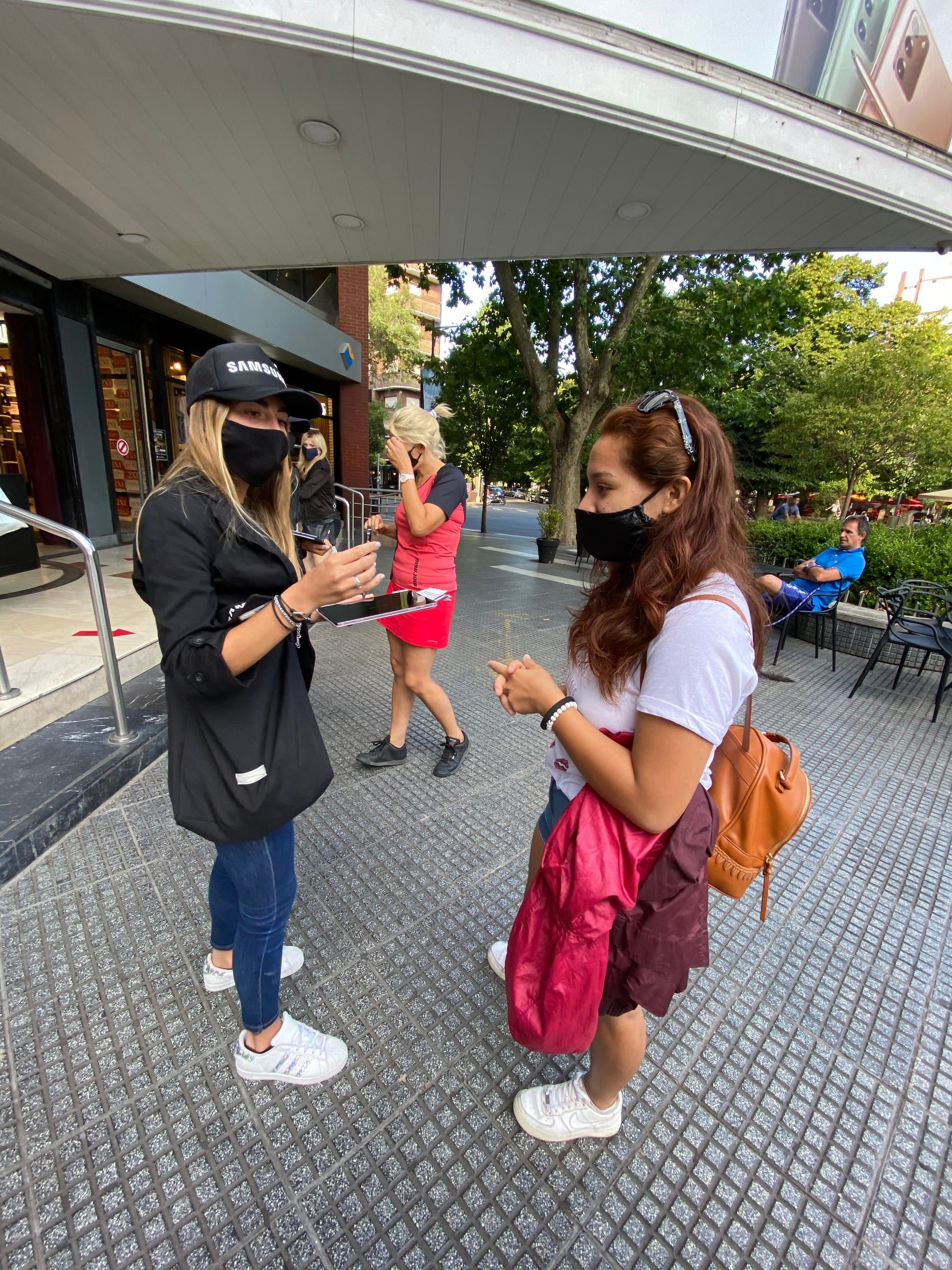 Promotoras de Samsung mostrando la promoción en tablet a una clienta en la calle