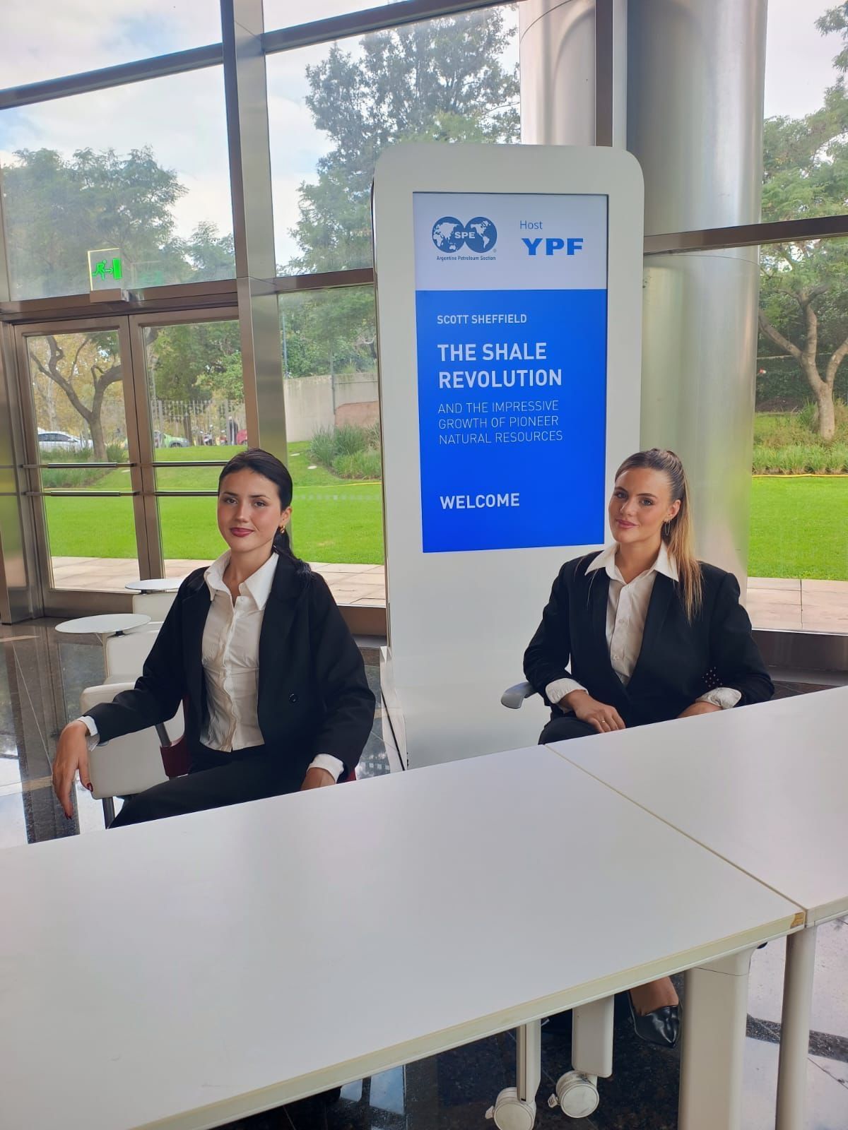 Dos recepcionistas en la mesa de acreditación de una conferencia de SPE con YPF como anfitrión